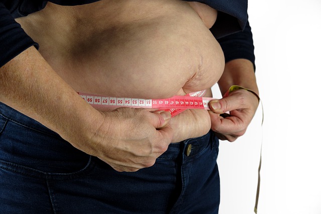 muž si měří tlusté břicho metrem